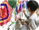壁を絵具で塗る子ども